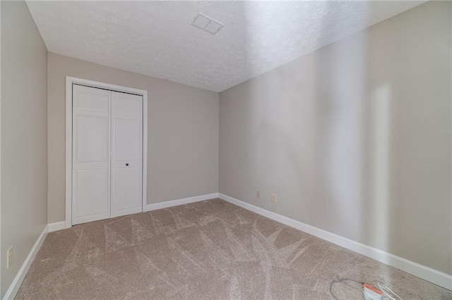 unfurnished bedroom with a closet, a textured ceiling, and carpet