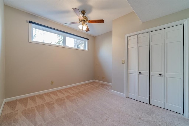 unfurnished bedroom featuring ceiling fan, light colored carpet, and a closet