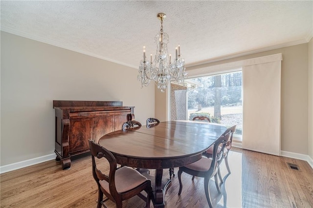 dining area with an inviting chandelier, ornamental molding, light hardwood / wood-style floors, and a textured ceiling