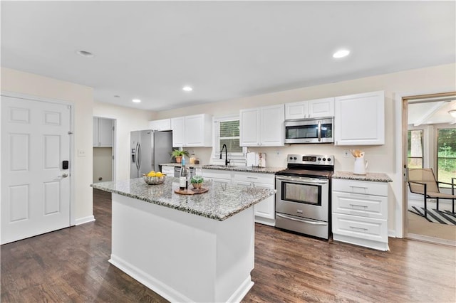 kitchen with appliances with stainless steel finishes, white cabinetry, light stone countertops, and sink