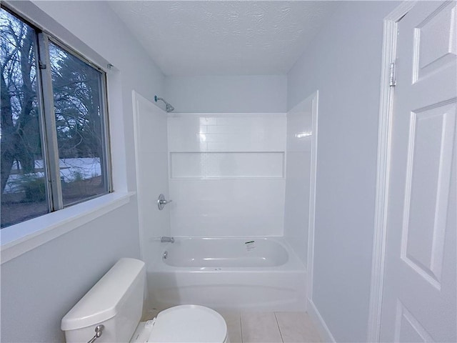 bathroom featuring toilet, bathing tub / shower combination, tile patterned flooring, and a textured ceiling