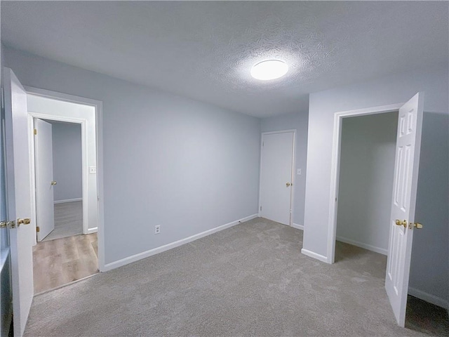 unfurnished bedroom featuring light carpet, a textured ceiling, and a closet