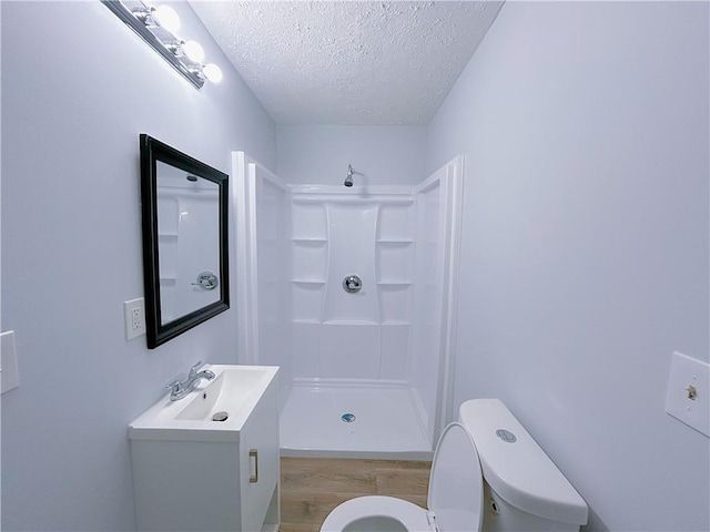 bathroom with walk in shower, toilet, wood-type flooring, a textured ceiling, and vanity