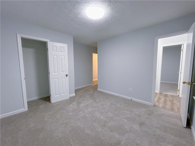 unfurnished bedroom with light carpet, a closet, and a textured ceiling