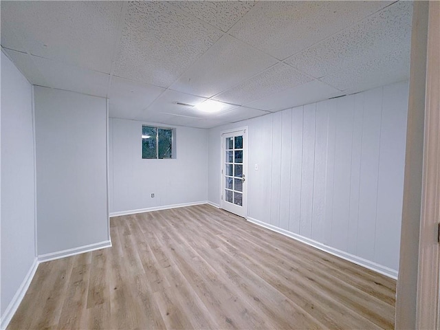 spare room with light hardwood / wood-style flooring and a paneled ceiling