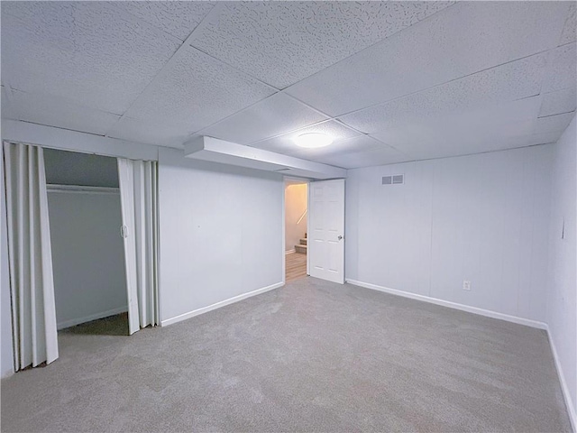 basement with a paneled ceiling and carpet flooring