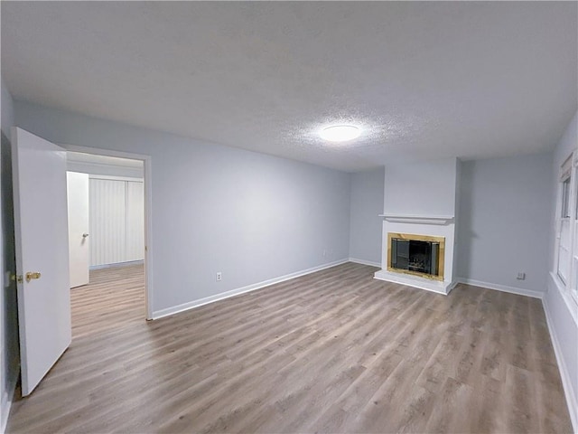 unfurnished living room with a textured ceiling and light wood-type flooring