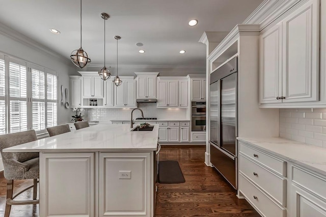 kitchen featuring appliances with stainless steel finishes, a breakfast bar, pendant lighting, and a kitchen island with sink