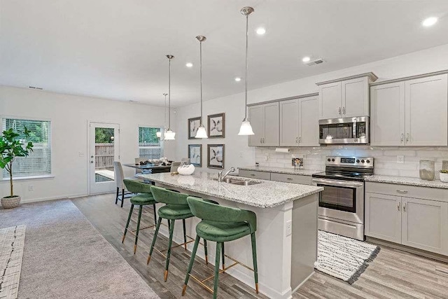 939 Brittfield Way, Loganville, GA 30052 - kitchen with stainless steel appliances, light wood finished floors, gray cabinetry, backsplash, and recessed lighting