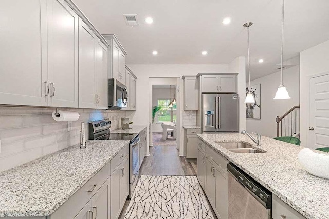939 Brittfield Way, Loganville, GA 30052 - kitchen featuring stainless steel appliances, gray cabinetry, tasteful backsplash, light stone countertops, and hanging light fixtures