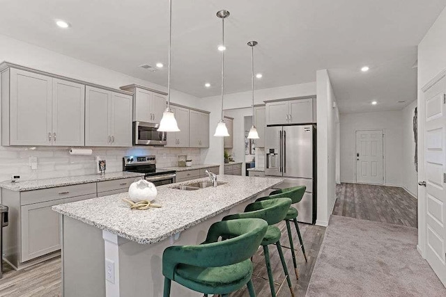 939 Brittfield Way, Loganville, GA 30052 - kitchen featuring appliances with stainless steel finishes, a breakfast bar area, a kitchen island with sink, gray cabinetry, and recessed lighting