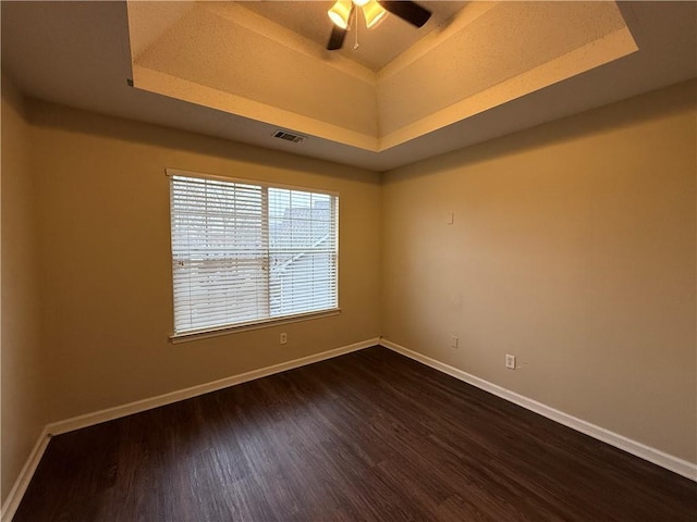 unfurnished room featuring baseboards, a raised ceiling, visible vents, and dark wood finished floors