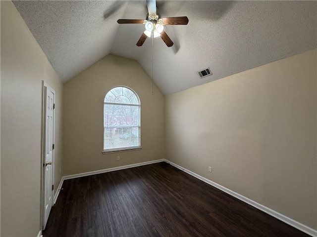 unfurnished room with visible vents, baseboards, lofted ceiling, wood finished floors, and a textured ceiling