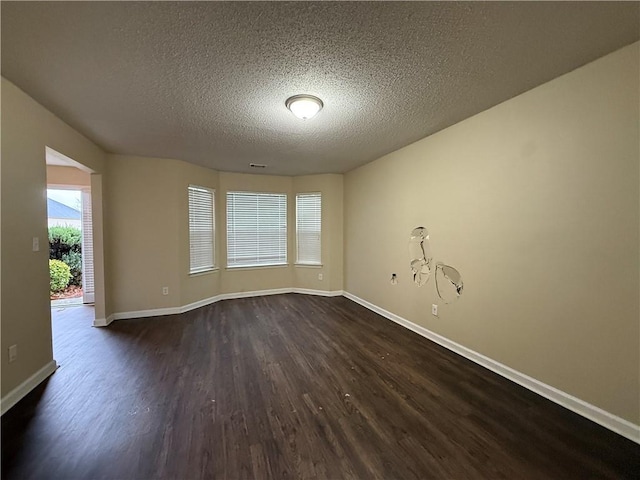 spare room featuring baseboards, dark wood-style flooring, and a textured ceiling