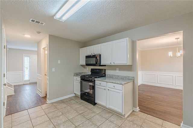 105 Kentwood Springs Dr, Hampton, GA 30228 - kitchen with a textured ceiling, visible vents, light tile patterned flooring, a decorative wall, and black appliances