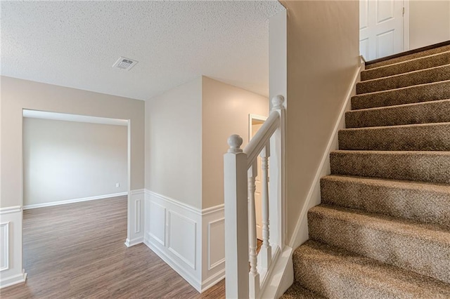 105 Kentwood Springs Dr, Hampton, GA 30228 - staircase featuring wainscoting, visible vents, a textured ceiling, and wood finished floors