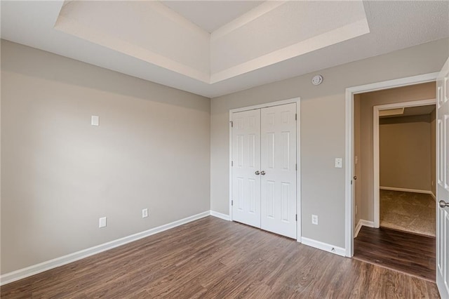 105 Kentwood Springs Dr, Hampton, GA 30228 - unfurnished bedroom featuring a tray ceiling, baseboards, a closet, and dark wood finished floors