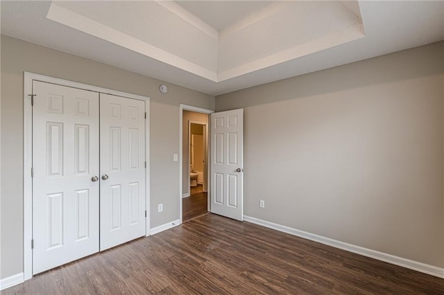 105 Kentwood Springs Dr, Hampton, GA 30228 - unfurnished bedroom featuring baseboards, a closet, a tray ceiling, and dark wood-style floors