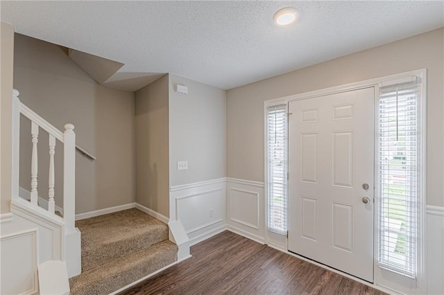 105 Kentwood Springs Dr, Hampton, GA 30228 - entryway featuring a textured ceiling, stairs, a wainscoted wall, and dark wood-style floors