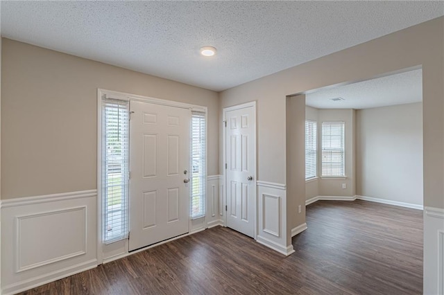 105 Kentwood Springs Dr, Hampton, GA 30228 - entryway with wainscoting, a textured ceiling, a decorative wall, and dark wood-type flooring