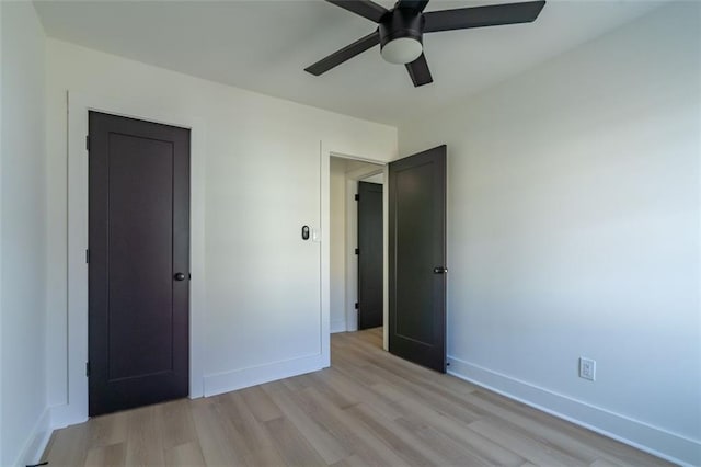 unfurnished bedroom with baseboards, a ceiling fan, and light wood-style flooring