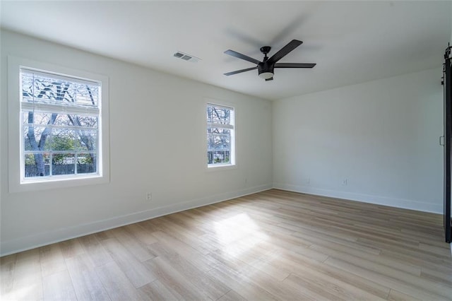 unfurnished room with visible vents, a wealth of natural light, and light wood finished floors
