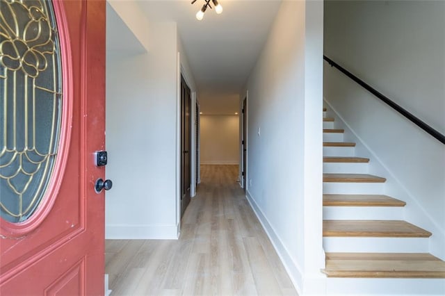entryway featuring stairway, baseboards, and light wood finished floors