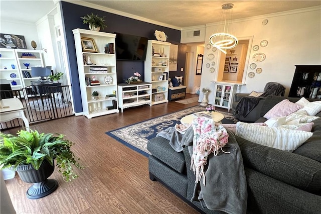 living room featuring dark hardwood / wood-style floors, an inviting chandelier, and crown molding