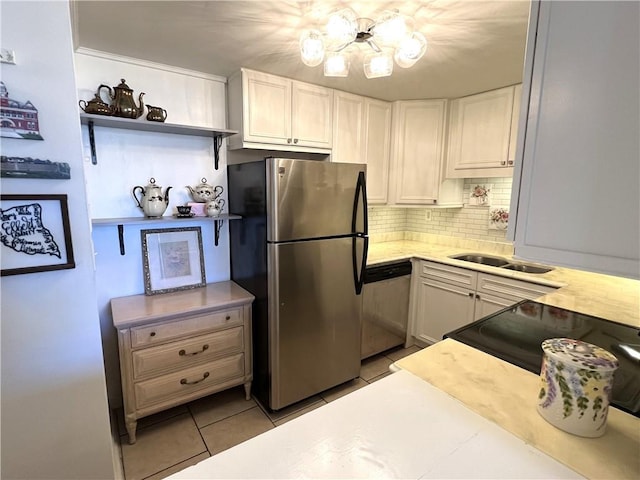 kitchen featuring appliances with stainless steel finishes, backsplash, sink, light tile patterned floors, and white cabinets