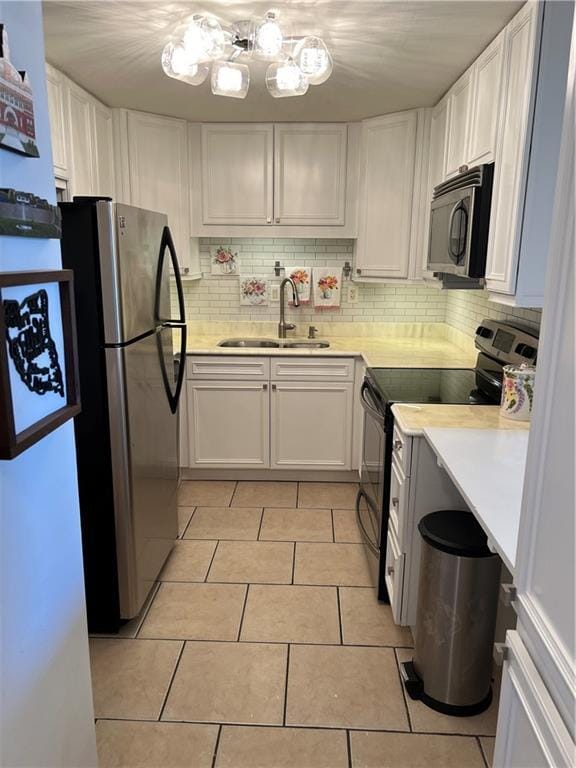 kitchen with backsplash, white cabinets, sink, light tile patterned floors, and appliances with stainless steel finishes