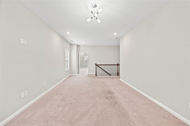 empty room featuring light carpet and a notable chandelier