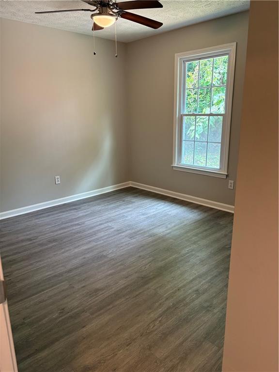 6103 Chaseland Dr, Rex, GA 30273 - empty room with ceiling fan, a textured ceiling, dark wood-type flooring, and baseboards