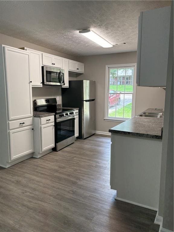 6103 Chaseland Dr, Rex, GA 30273 - kitchen featuring stainless steel appliances, dark wood-type flooring, a sink, white cabinets, and dark countertops