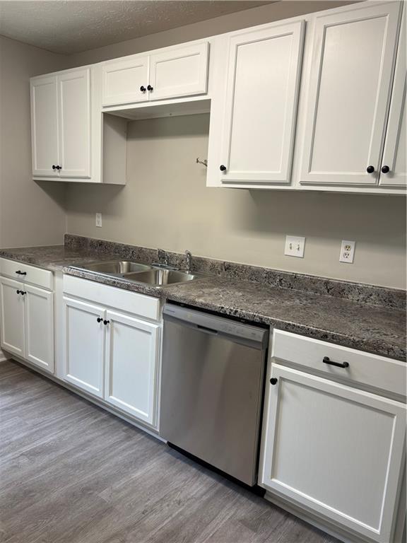 6103 Chaseland Dr, Rex, GA 30273 - kitchen with stainless steel dishwasher, a sink, white cabinetry, and light wood finished floors