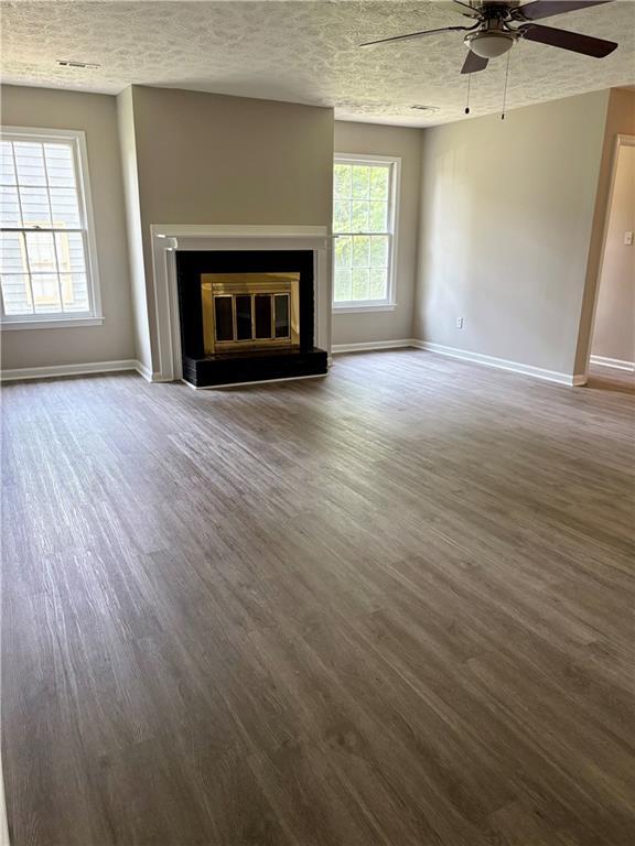 6103 Chaseland Dr, Rex, GA 30273 - unfurnished living room with ceiling fan, baseboards, wood finished floors, a glass covered fireplace, and a textured ceiling