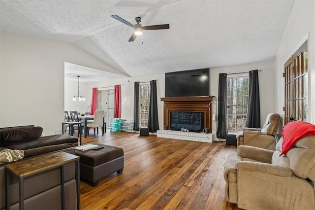 living room featuring hardwood / wood-style flooring, ceiling fan, a textured ceiling, a brick fireplace, and vaulted ceiling