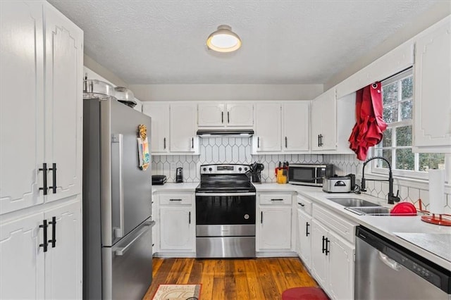 kitchen with stainless steel appliances, white cabinetry, sink, and decorative backsplash