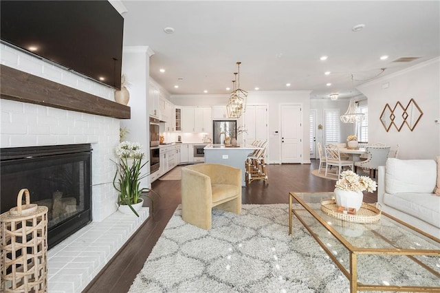 living room with recessed lighting, dark wood-type flooring, a fireplace, visible vents, and crown molding