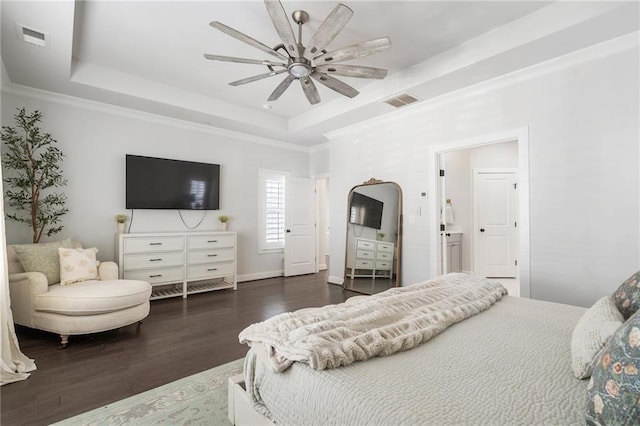 bedroom with ornamental molding, a tray ceiling, visible vents, and wood finished floors