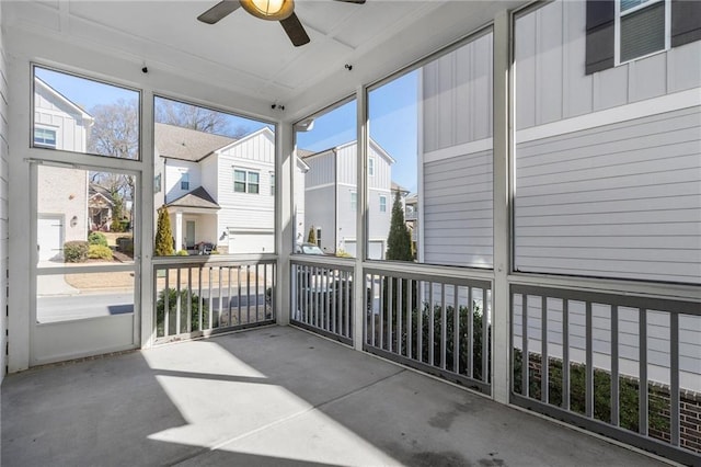 unfurnished sunroom featuring a residential view and a ceiling fan