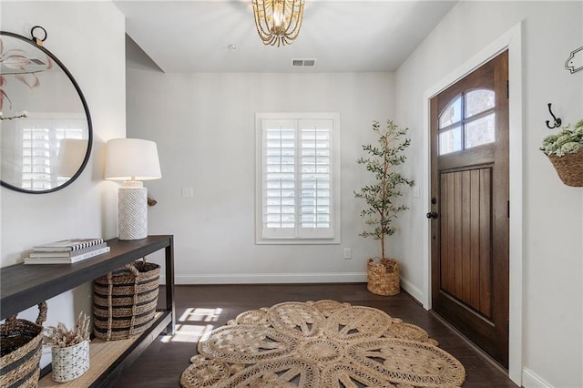 foyer with a chandelier, visible vents, baseboards, and wood finished floors