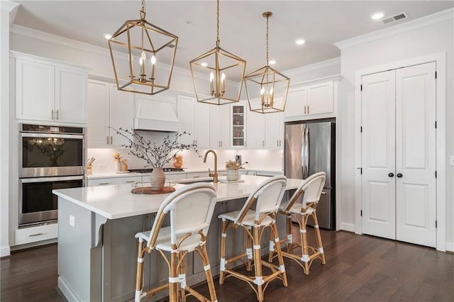 kitchen with premium range hood, a sink, light countertops, appliances with stainless steel finishes, and dark wood finished floors