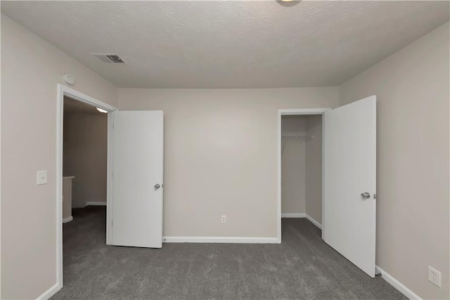 unfurnished bedroom featuring dark carpet, a textured ceiling, and a closet