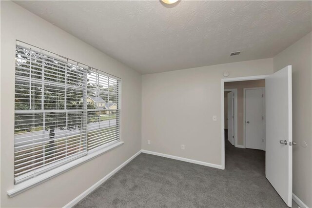 carpeted empty room with a textured ceiling