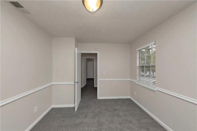 carpeted empty room with a textured ceiling