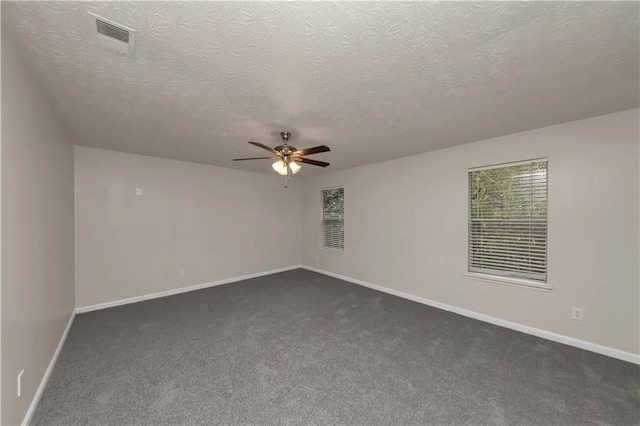 spare room featuring ceiling fan, a textured ceiling, and dark colored carpet