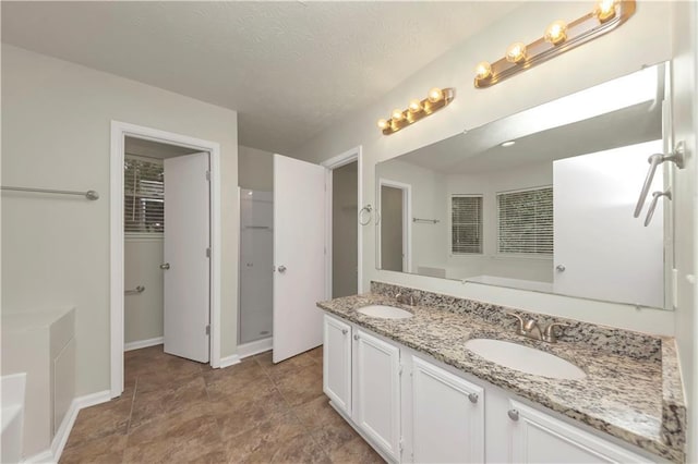 bathroom featuring a tub, vanity, and a textured ceiling