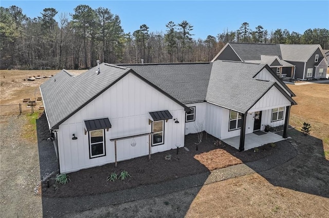 view of front of property featuring metal roof, a patio, a shingled roof, and board and batten siding