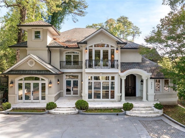 rear view of house featuring a balcony and french doors