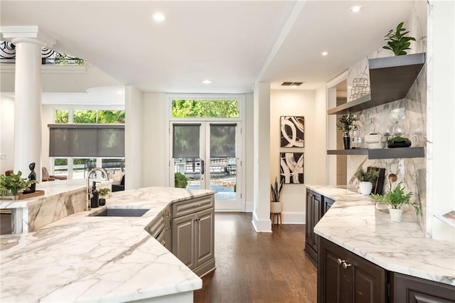 kitchen with dark wood-type flooring, light stone counters, tasteful backsplash, dark brown cabinets, and sink